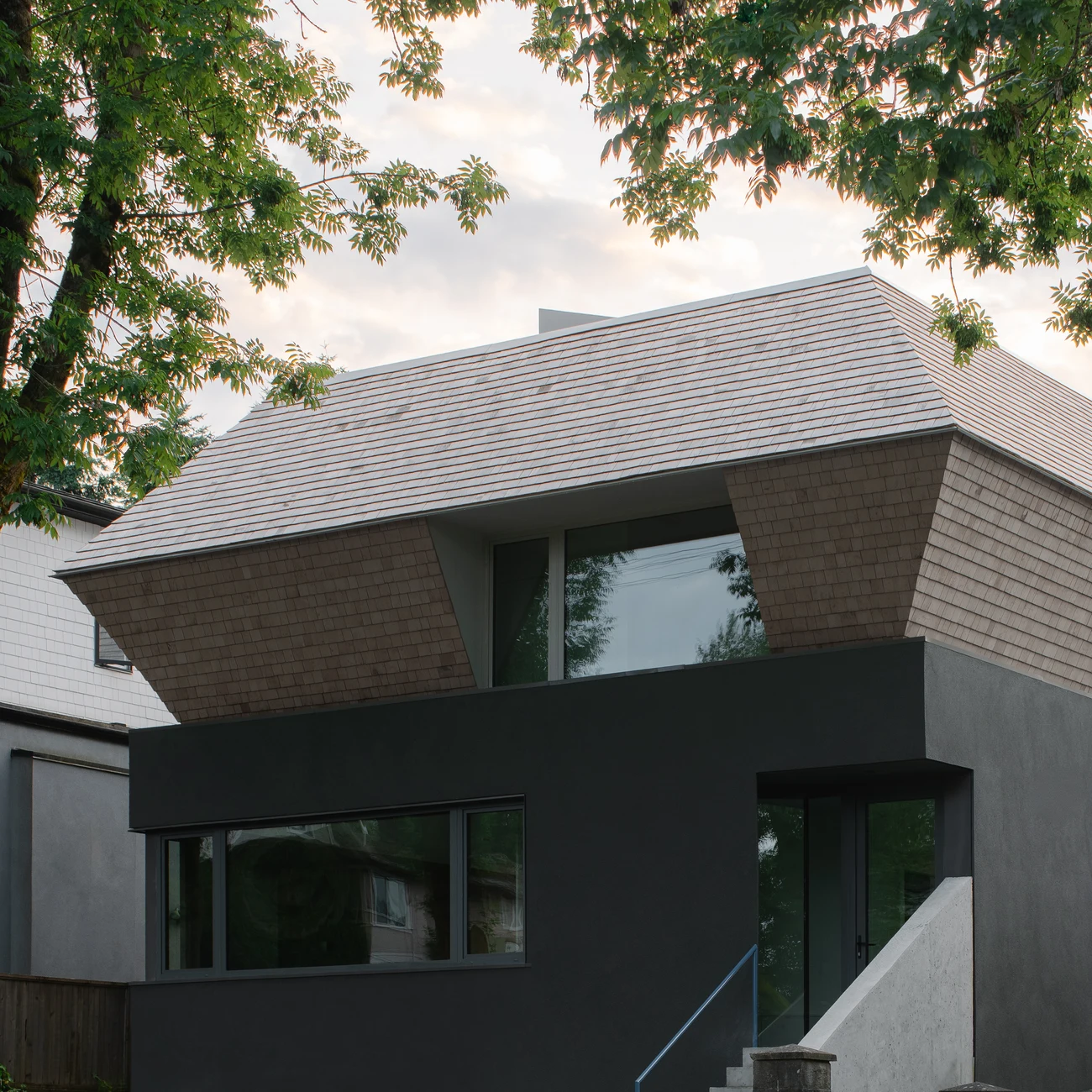 Trout Lake Infill’s shingled roof and entrance framed closely beneath a tree canopy