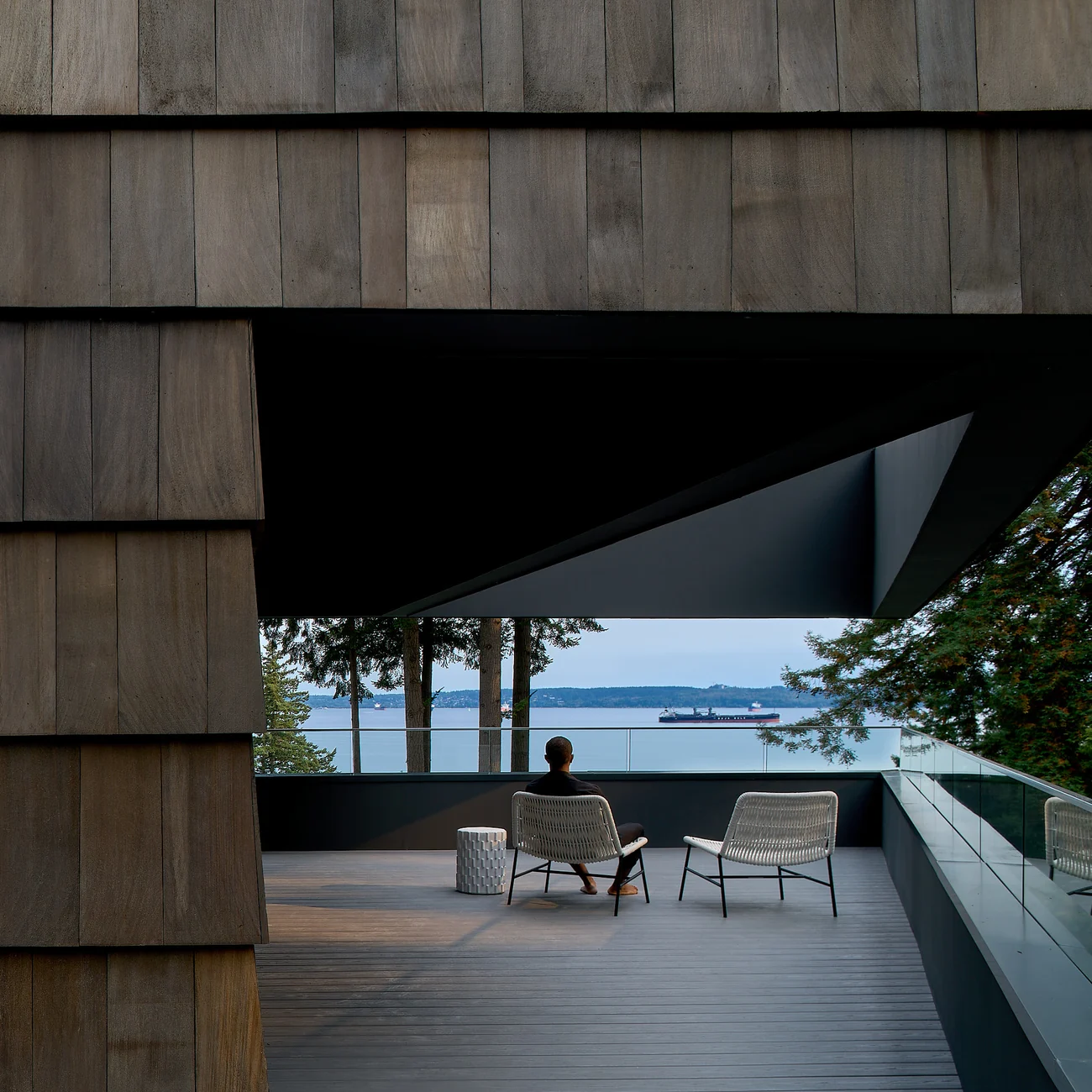 A seated person on the cedar-framed balcony overlooking the water