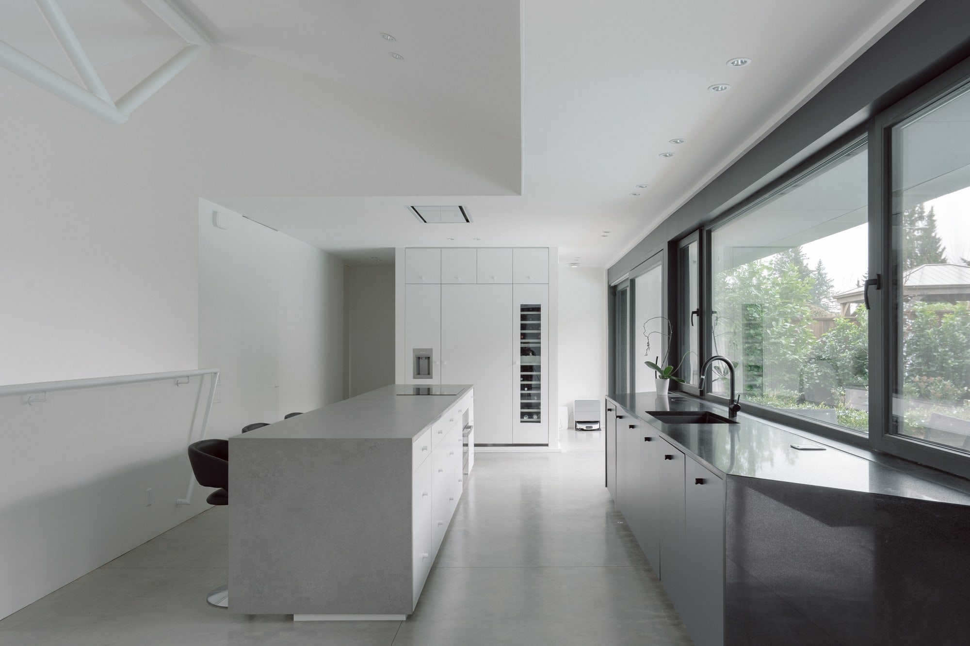Photography: Shane Hauser Baycrest — Kitchen island and dark cabinetry beside long garden-facing windows