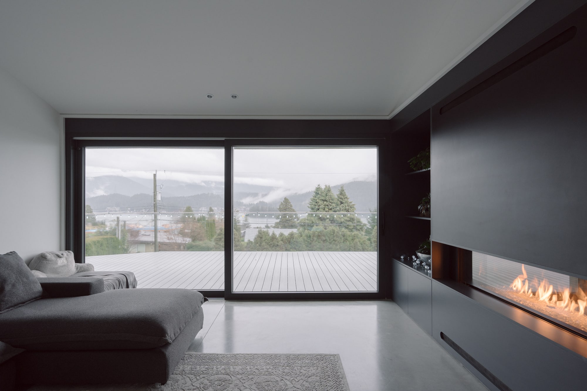 Photography: Shane Hauser Baycrest — Living room fireplace beside broad glazing and inlet views
