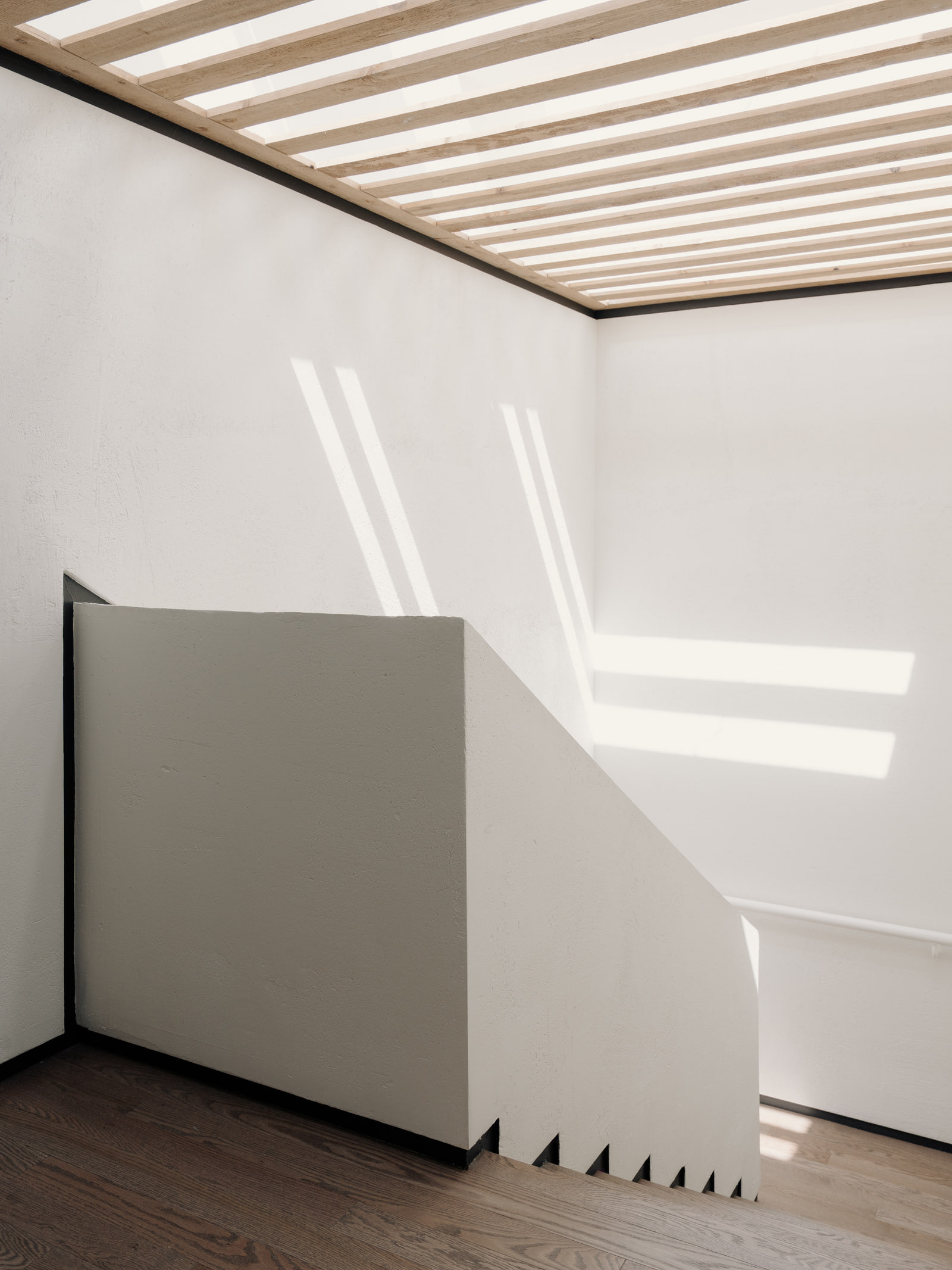 Daylight from the slatted skylight falling across the stair.