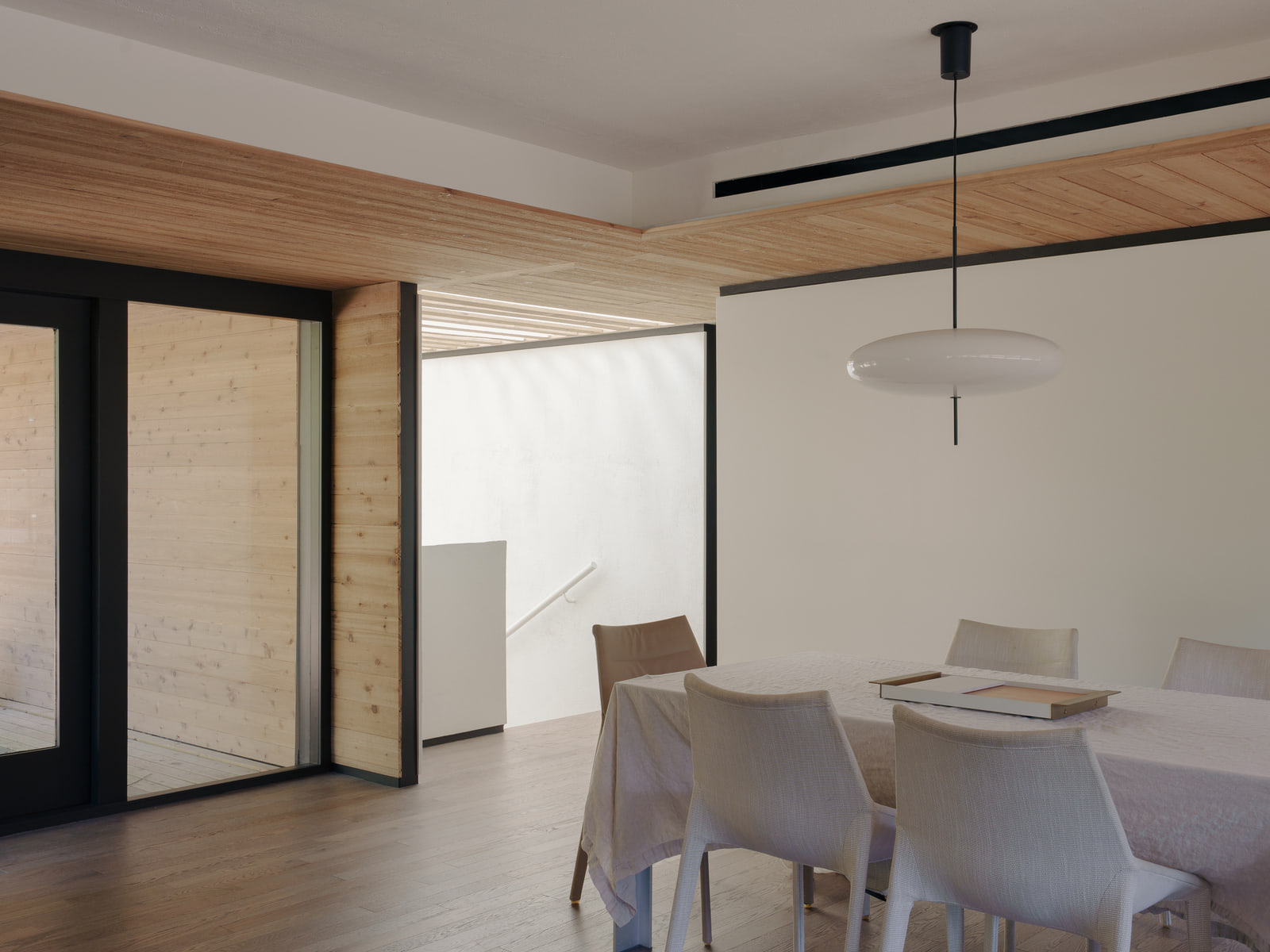 Dining room with timber ceiling transitions and garden light.