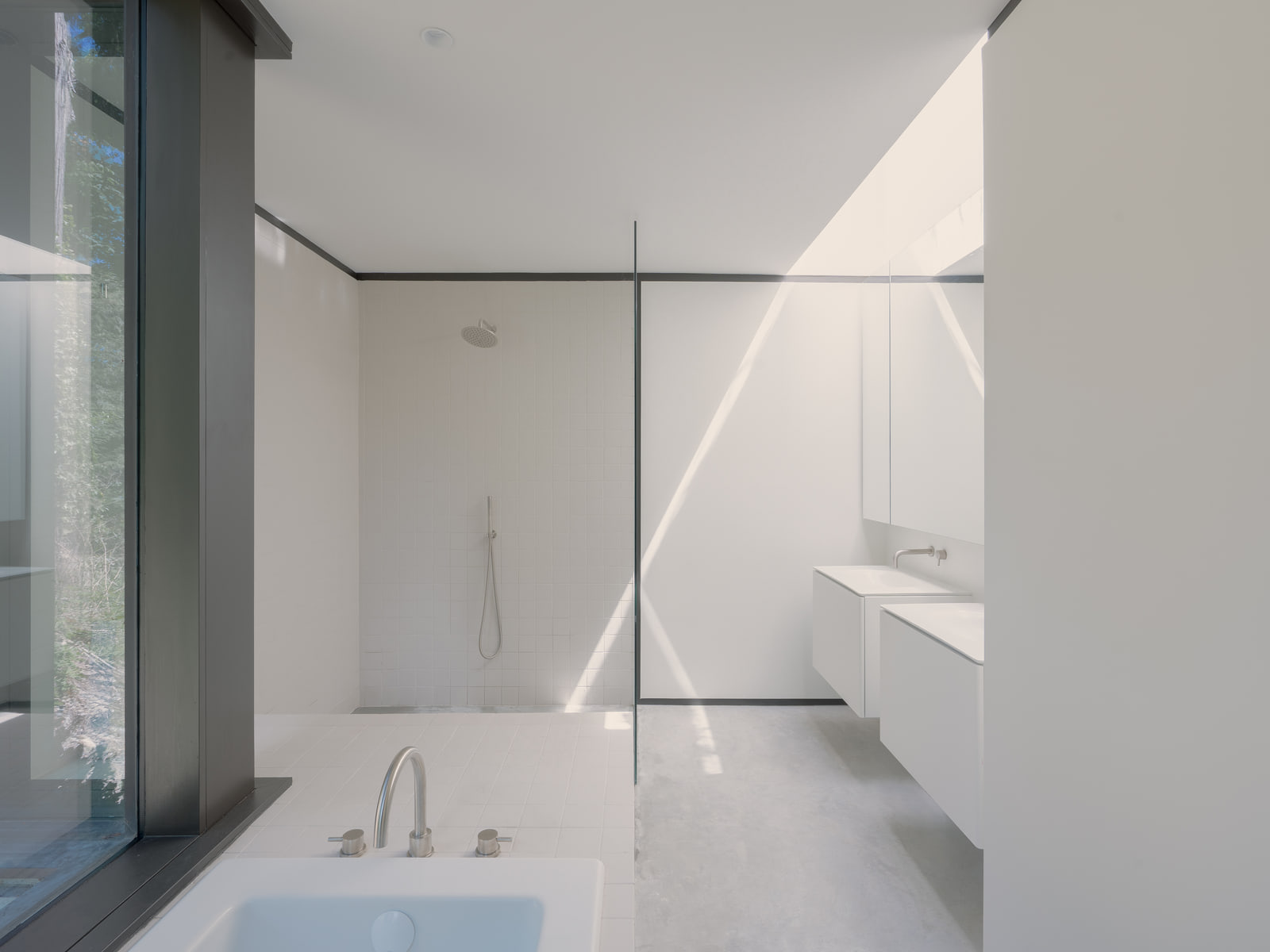 Daylit bathroom with white surfaces and a framed garden view.
