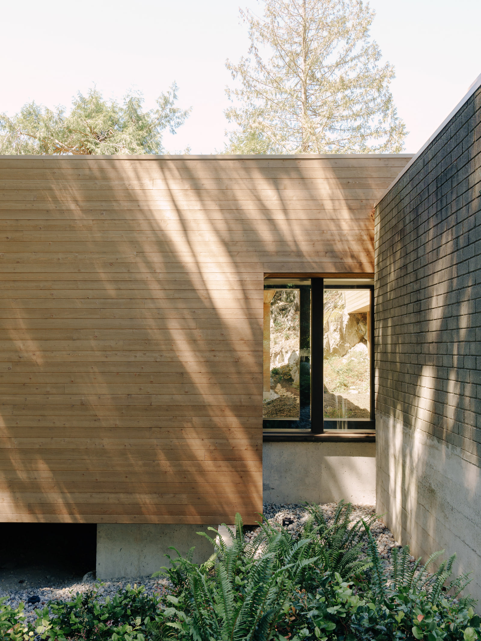 Sunlight crossing the cedar-clad bedroom wing at Fells House.