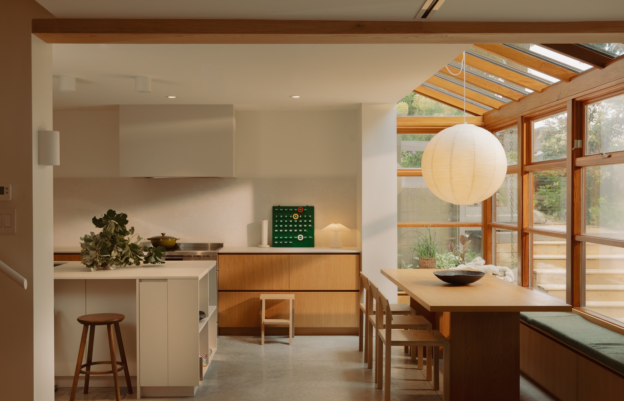 Kitchen and dining spaces framed by timber openings and garden-facing glazing.