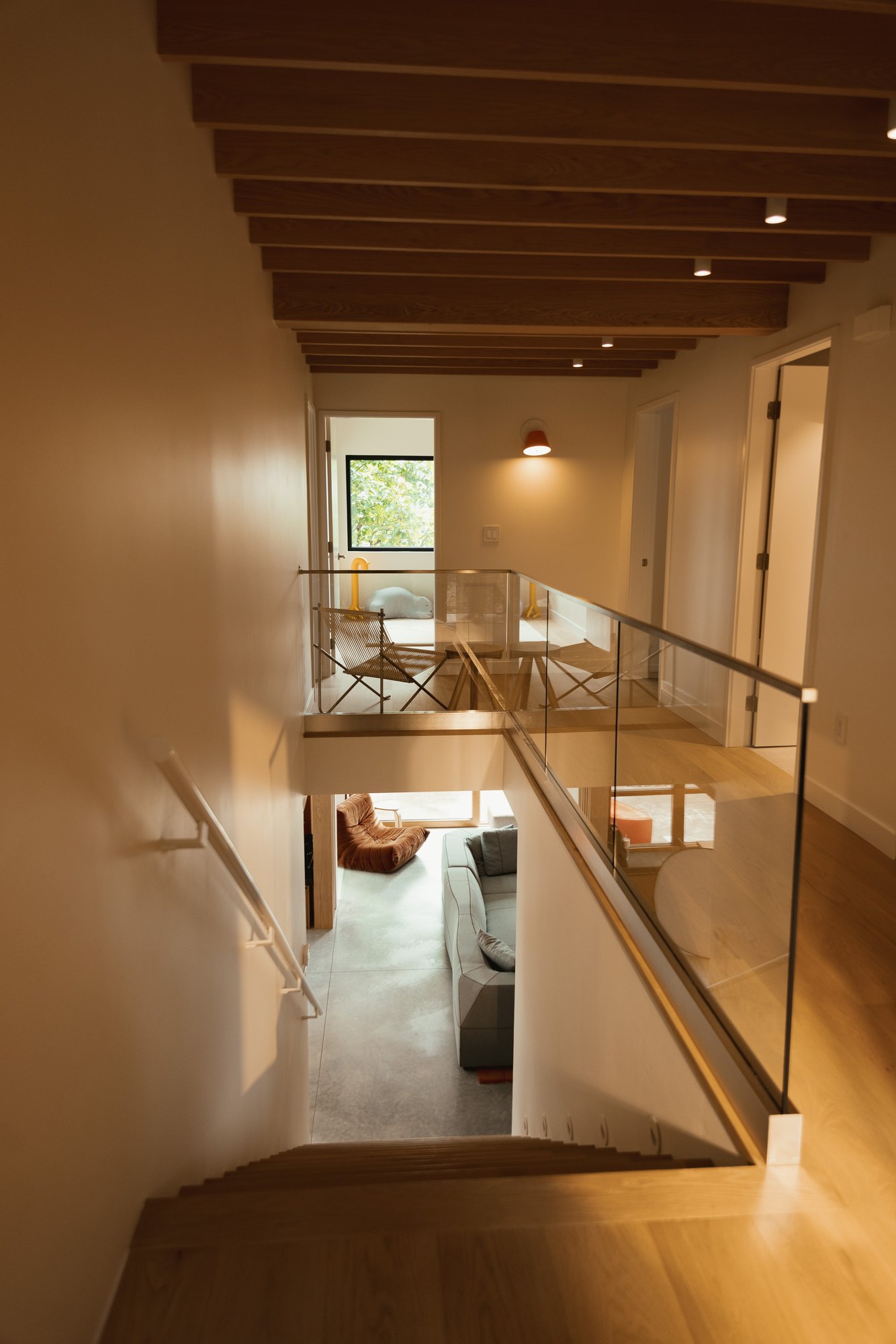 Stair descending beside the glass balustrade into the living space.